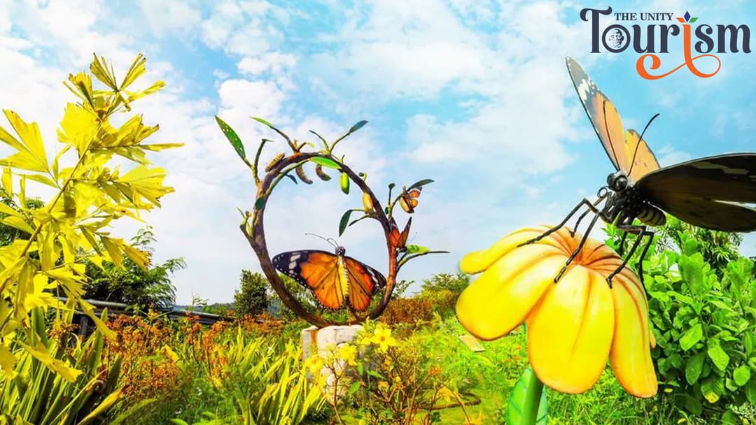 Colorful butterfly sculptures on flowers and plants at Statue of Unity Butterfly Garden under bright sky.