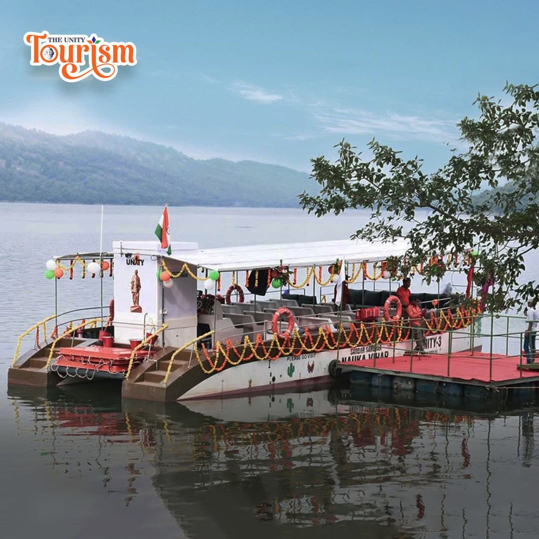 Two decorated boats docked on a serene lake with lush mountains in the background under a clear blue sky.