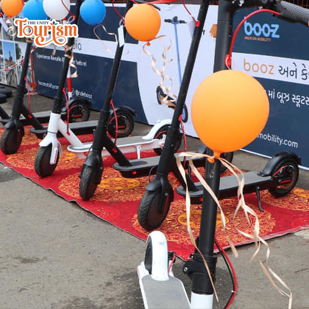 Line of electric kick scooters with Statue of Unity in the background.