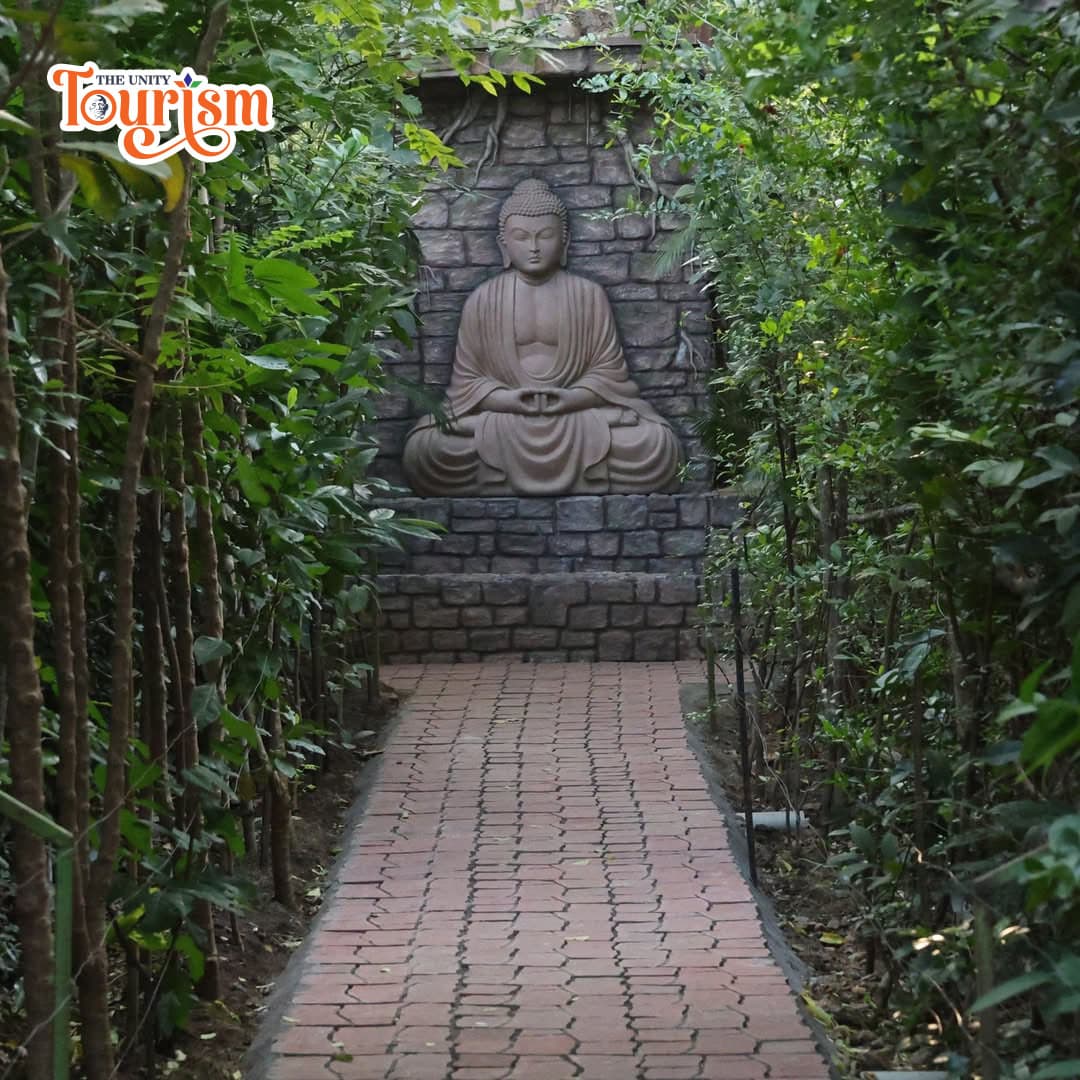 Tranquil green path leading to Buddha statue at Miyawaki Forest, Unity Tourism