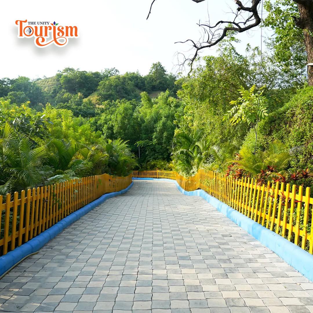 A scenic walkway featuring a yellow fence, surrounded by trees in the background, creating a peaceful atmosphere.
