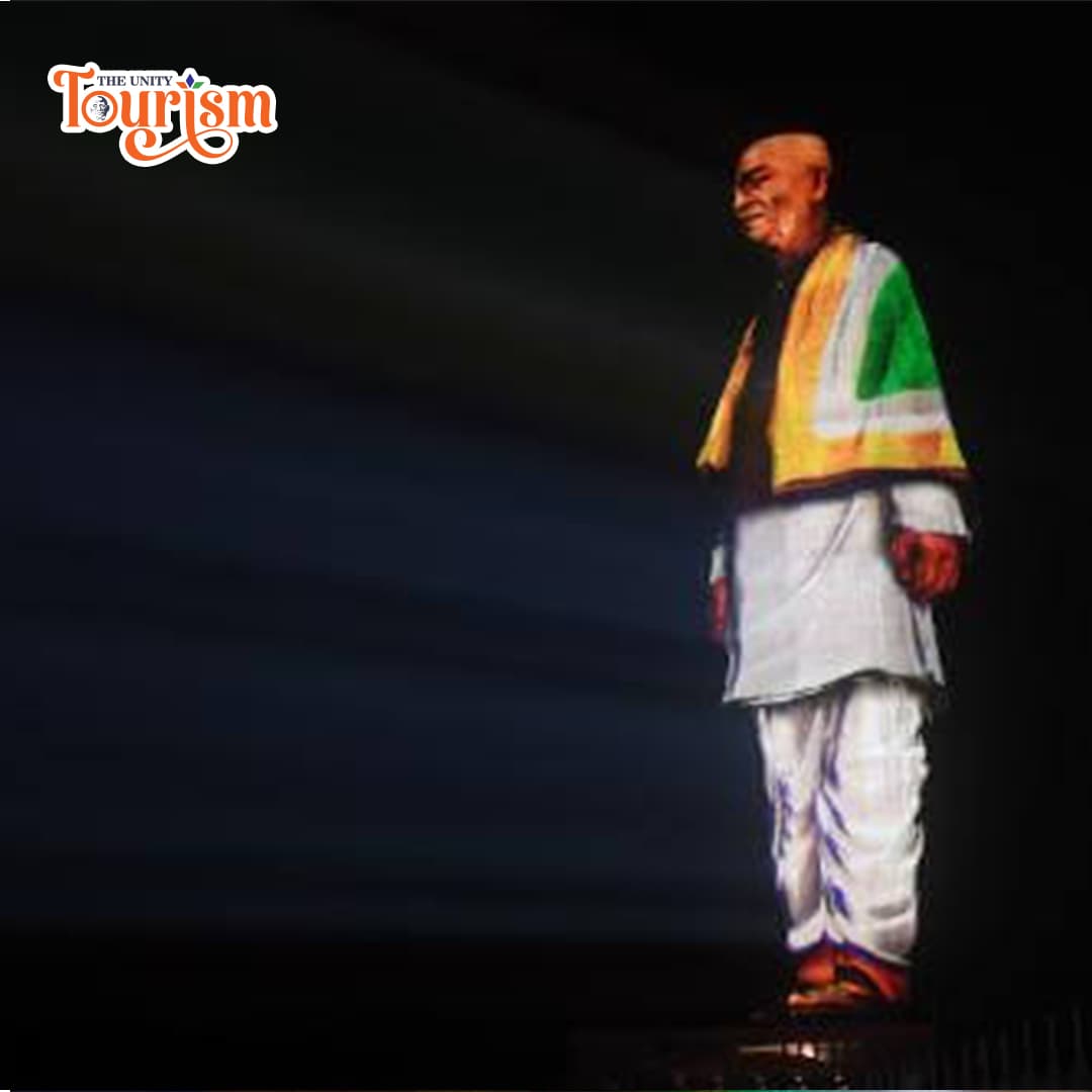 Statue of Unity glowing in multicolored lights during laser projection show.