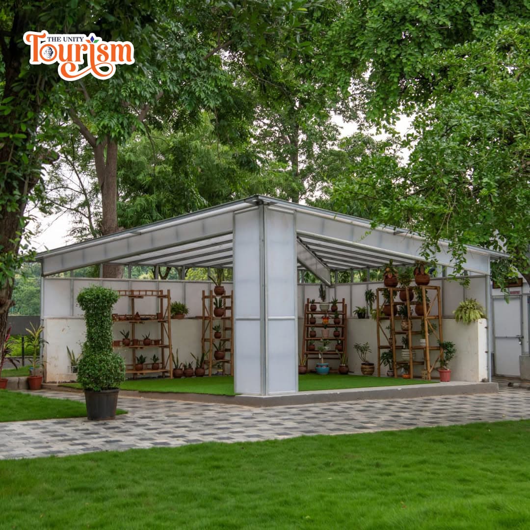 Wide landscape view of Valley of Flowers with Statue of Unity in the background.