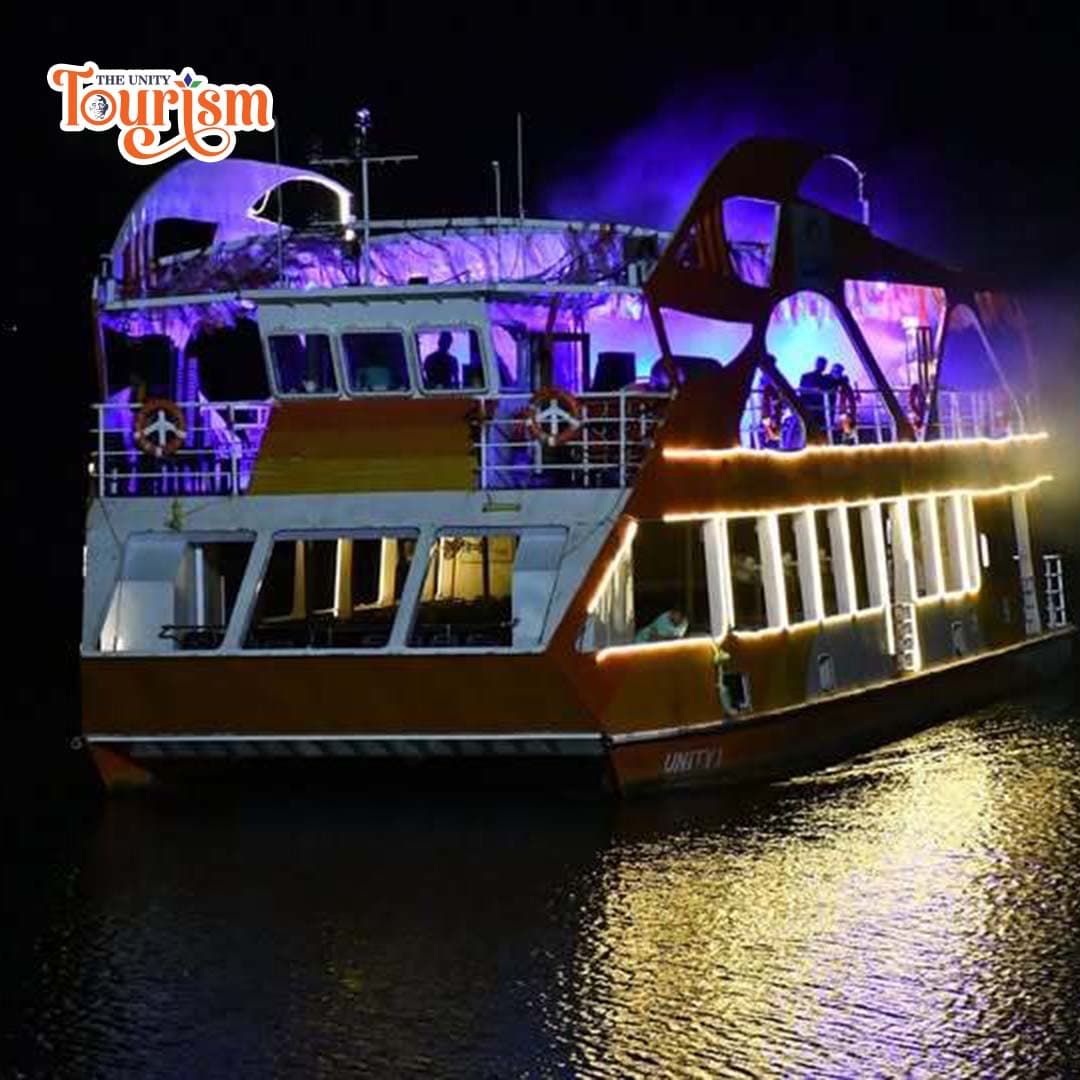 Ekta Dinner Cruise illuminated with colorful lights reflecting on the water at night.