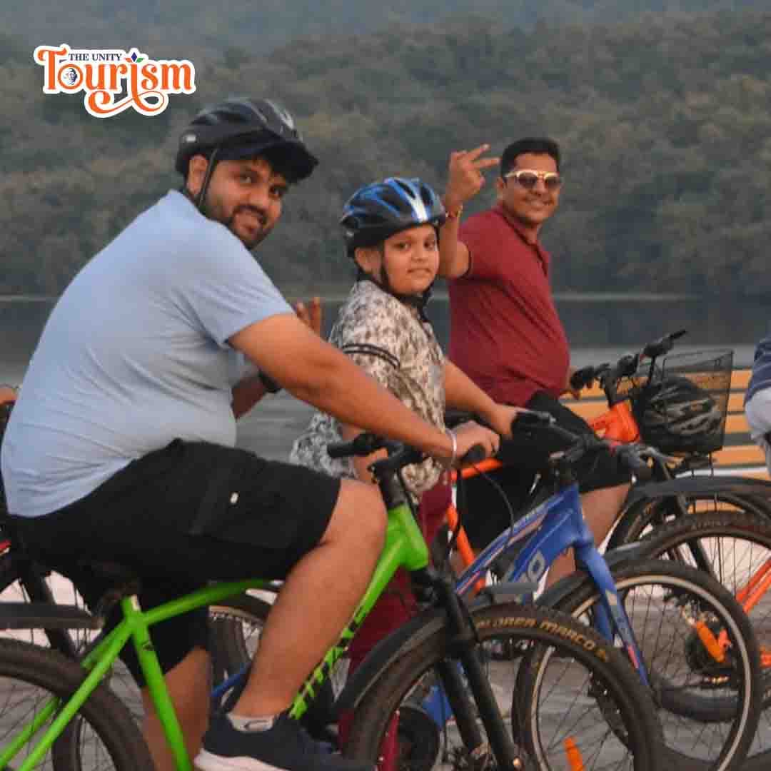 Tourists riding bicycles with beautiful Statue of Unity riverfront view